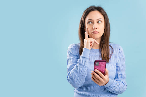 istock Young woman ponders on how to answer question on blue background 1353066671