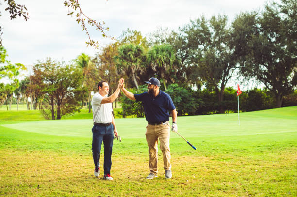 istock Two male golfers high five on a golf course 1353066759