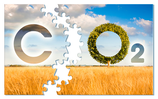 Reduction of the amount of CO2 emissions - concept image in jigsaw puzzle shape with CO2 icon text and tree shape in rural scene