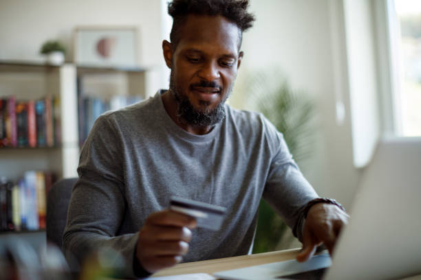 istock Young smiling man using credit card and laptop for shopping online 1353067906