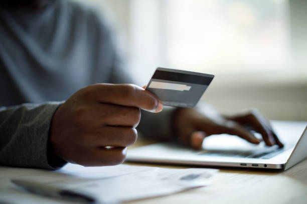 hombre usando tarjeta de crédito y computadora portátil para compras en línea - pagar fotografías e imágenes de stock