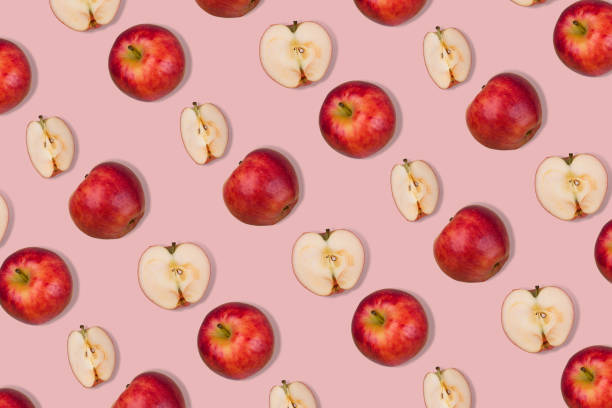 istock Outstanding pattern of fresh whole apple and halves on  pastel pink background. 1353067979