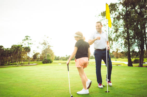 istock Father and daughter on the golf course enjoying a sunny day playing a round 1353067990