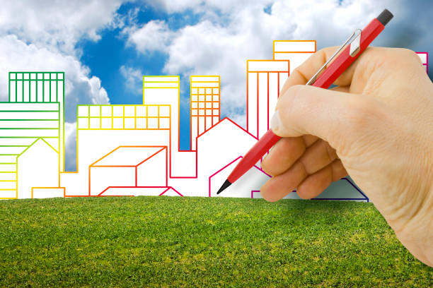 istock Architect planning a new city - construction industry concept with an imaginary cityscape with buildings against a green area 1353069025