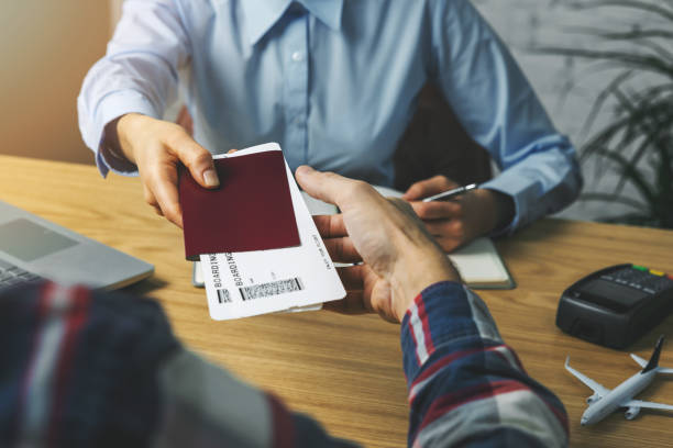 travel agent giving flight tickets and documents to customer in agency office stock photo