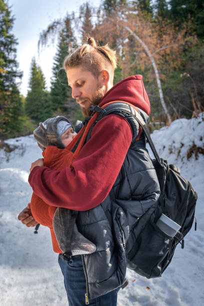 istock Little boy sleeping in his father's sling while walking in the winter forest 1353072780
