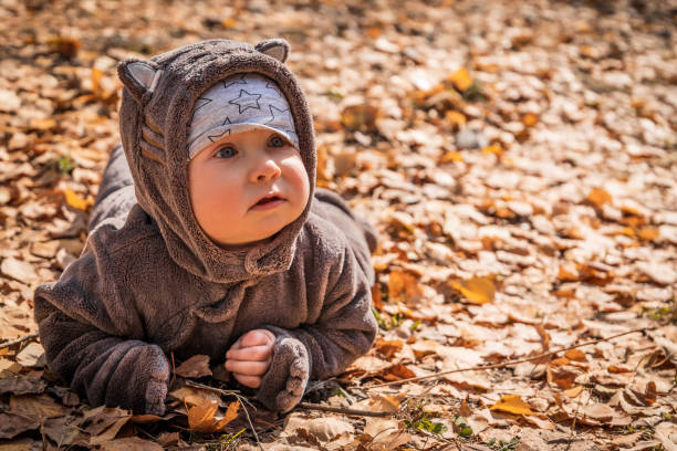 istock Little baby boy playing in yellow fall foliage, copy space 1353072800