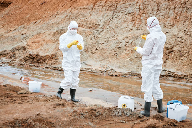 istock Environmental scientists in masks, gloves and protective suits working with toxic substances on polluted area 1353076385