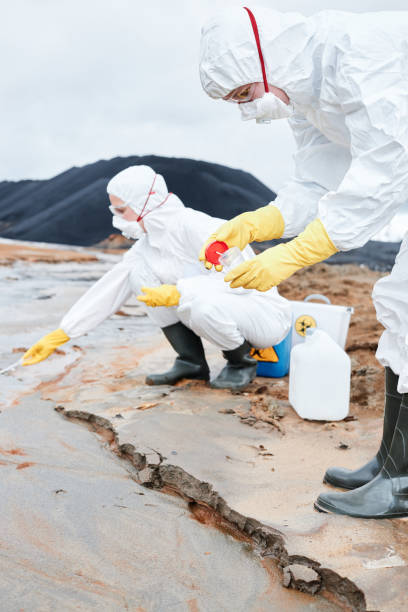 istock Environmental scientists in protective suits and respirators putting samples into containers whilr researching contaminated samples in toxic area 1353076512