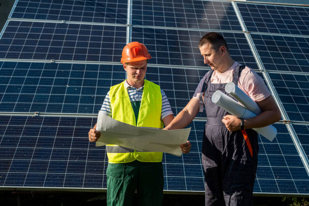 istock near the new solar panels, two young workers in uniform stand with a plan of work performed 1353076884