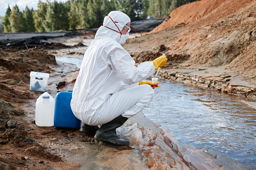 Land scientist dropping water sample into container