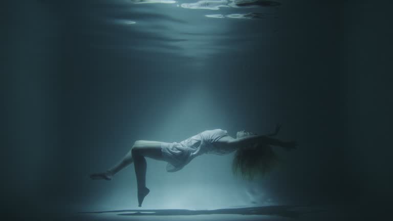 girl in a white dress swims underwater