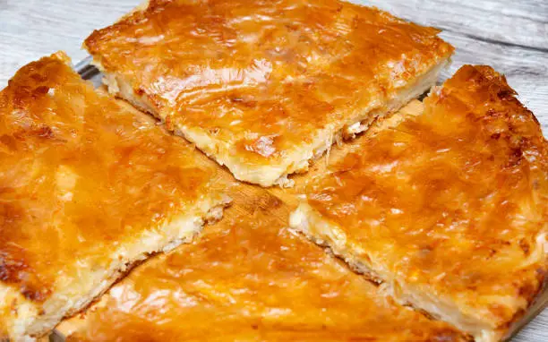 Traditional Balkan tasty pastry food - Burek with cheese, served fresh and sliced on a plate.