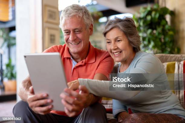 Happy Senior Couple Looking At Social Media On A Tablet Computer Stock Photo - Download Image Now