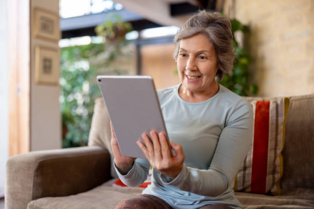 istock Senior woman on a video call using a tablet computer at home 1353083064