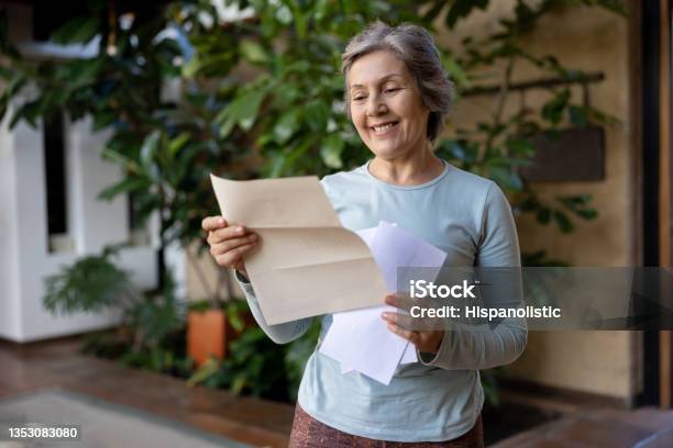 Happy Senior Woman Reading A Letter From The Mail Stock Photo - Download Image Now - Senior Adult, Mail, Letter - Document