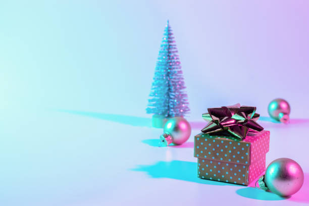 istock Neon xmas winter background. Holiday decoration bauble ball on neon gradient backdrop. Minimal abstract tree, xmas gift box. Happy new year copy space. 1353086491