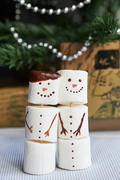 Photo of Two snowmans of marshmallow on the white table in Christmas time.