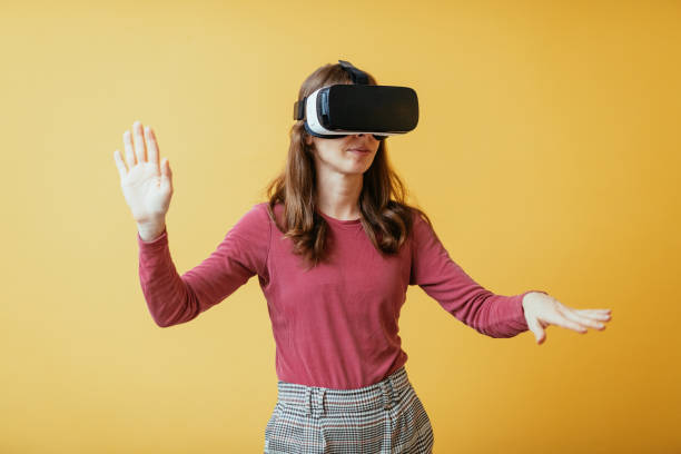 istock Unrecognisable Caucasian woman with Virtual Reality headset against yellow background 1353087686