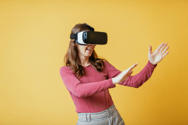 istock Unrecognisable Caucasian woman with Virtual Reality headset against yellow background 1353087694