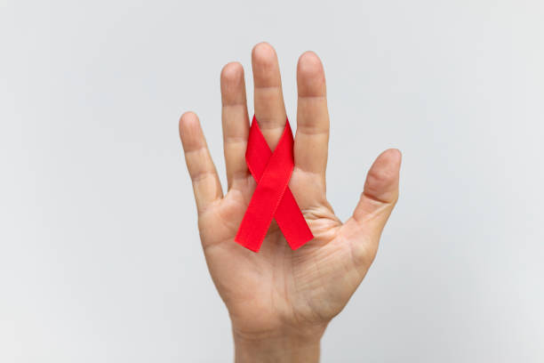 cinta con lazo rojo en los dedos de la mano. campaña de prevención del sida. día mundial de la lucha contra el cáncer - aids awareness ribbon fotos fotografías e imágenes de stock