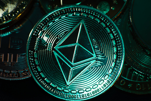 Horizontal view of cryptocurrency tokens including Ethereum seen from above on a black background with light trails. High quality photo