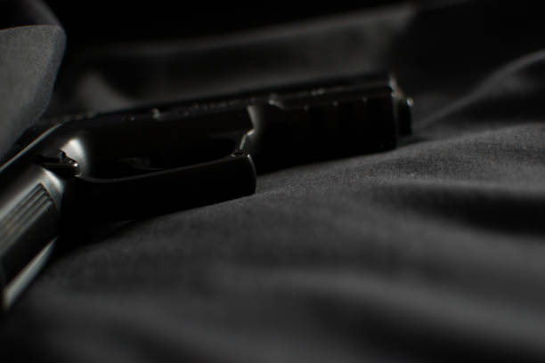 istock Black gun, pistol on black fabric background 1353098969