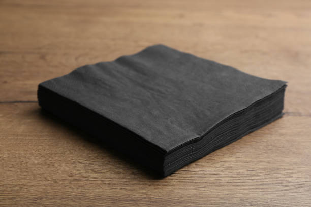 pila de pañuelos de papel negro limpio sobre mesa de madera - black backgound fotografías e imágenes de stock