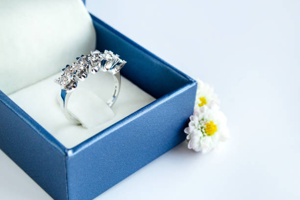 Close up (macro) of  gold, solitaire diamond engagement ring, shot from above, in an open red heart shaped box with white interior.