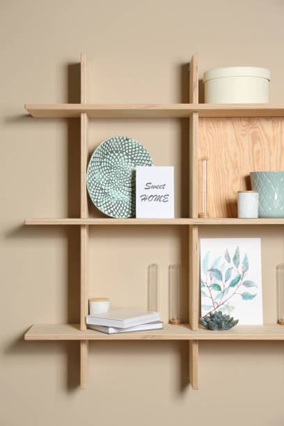 istock Wooden shelves with different decorative elements on beige wall 1353104277