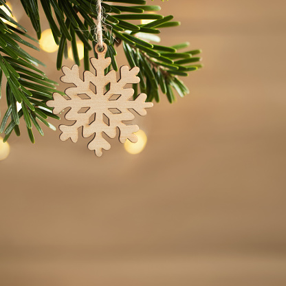 Zero waste and eco friendly christmas concept. Wooden snowflake on a Christmas tree branch on a background of a wooden wall. Horizontal banner with copy space.
