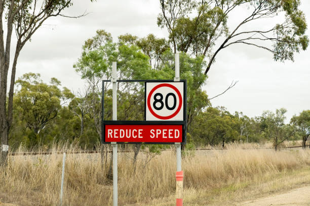 Speed Roadsign Reduce speed to 80 kilometers per hour signage in the Australian bush beside a road and in front of a railway line speed limit sign australia stock pictures, royalty-free photos & images