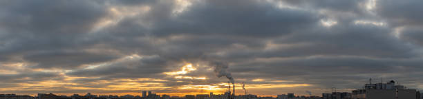 istock Wide panorama of cloudy sunrise or sunset over rooftops 1353109848