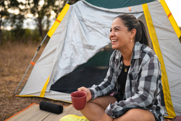 Woman drinking coffee at camp in forest