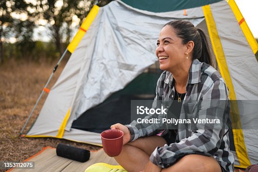 istock Woman drinking coffee at camp in forest 1353112075