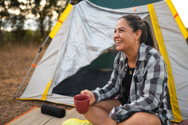 Woman drinking coffee at camp in forest stock photo