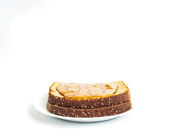 Side view of nutritious snack or lunch of a peanut butter and honey sandwich on whole wheat bread on white background