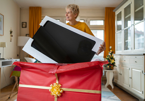 Woman taking out a big TV set from the box, she received it as a Christmas gift