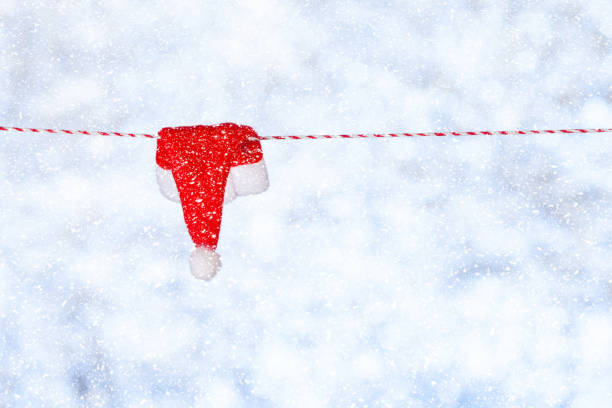 istock A small red Christmas cap hangs on a rope against a blurred shiny blue-gray background. Copy space. Blank for design, concept 1353132833