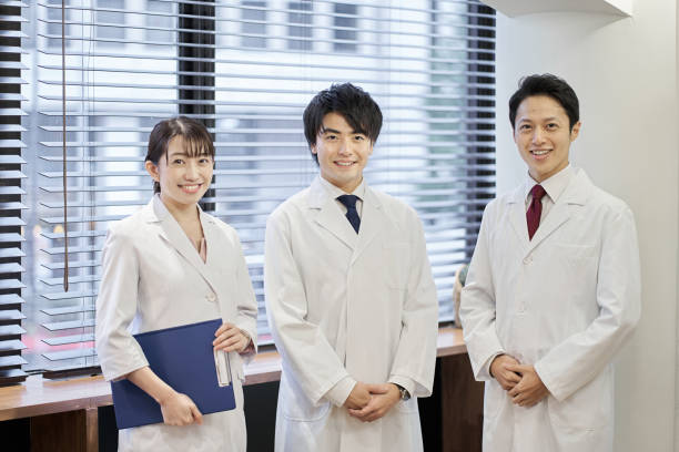 le personnel médical asiatique debout avec un sourire - healthcare and medicine smiling group of people lab coat photos et images de collection