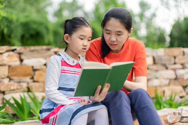 istock Little Girl and Mother Reading Book 1353140733