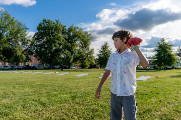 istock A young boy is tossing bean bags at a corn hole board during a summer afternoon with some clouds in the sky. 1353141514