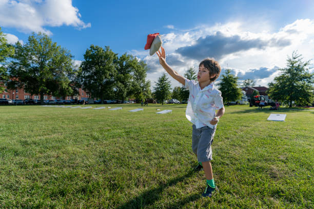 istock A young boy is tossing bean bags at a corn hole board during a summer afternoon with some clouds in the sky. 1353141516