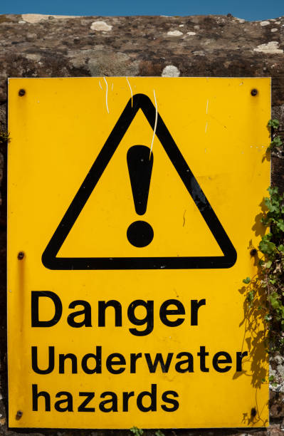 istock A yellow Danger Underwater Hazard warning sign fixed to a brick wall beside a river 1353147767