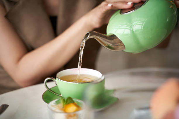 asian woman pouring tea into teacup
