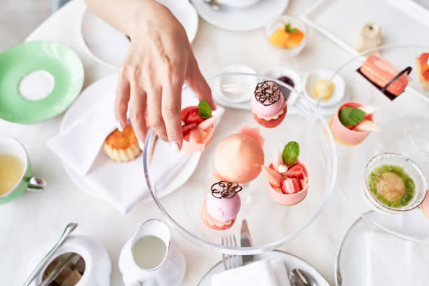 asian woman picking up dessert at dining table high angle view of hand of asian woman picking a dessert from glass plate on table chinese ethnicity china restaurant eating stock pictures, royalty-free photos & images