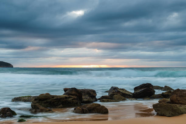 istock Low cloud covered sunrise seascape with rocks 1353157391