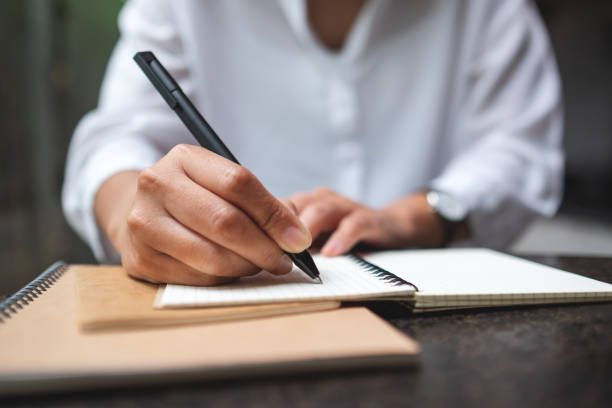 istock a woman writing on a notebook on the table 1353158323