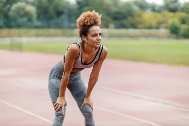 istock A tired, fit runner is standing in the stadium and taking a break after a long run on a rainy autumn day while listening music on earphones. Runner resting in the stadium. 1353161404
