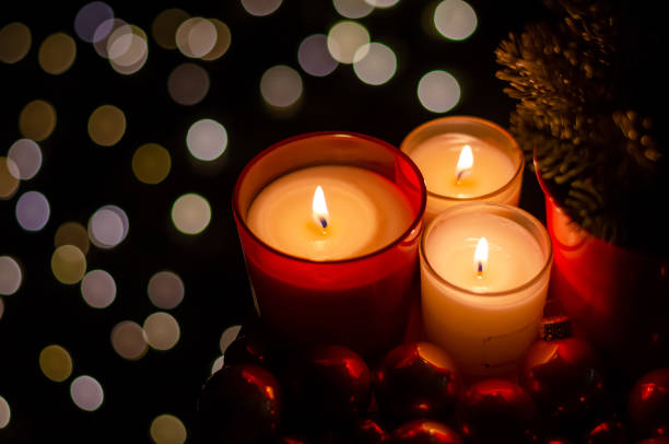 istock Burning candle in red glass with Christmas tree decorated with bauble ornaments 1353164384
